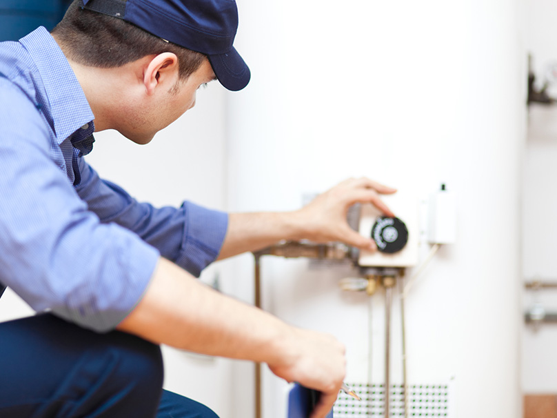 a plumber adjusting the settings on a water heater